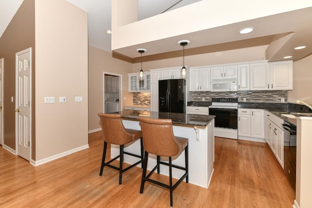 kitchen featuring white cabinetry, black appliances, a kitchen bar, and a sink