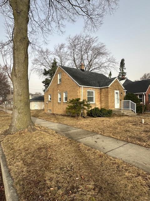 view of front of house featuring brick siding and a chimney