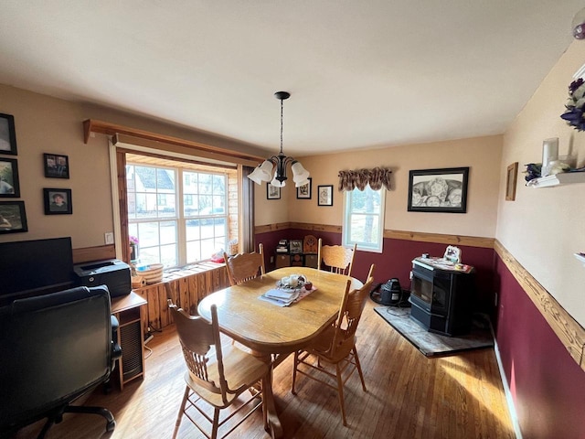 dining space with light wood-style flooring, a notable chandelier, and wainscoting