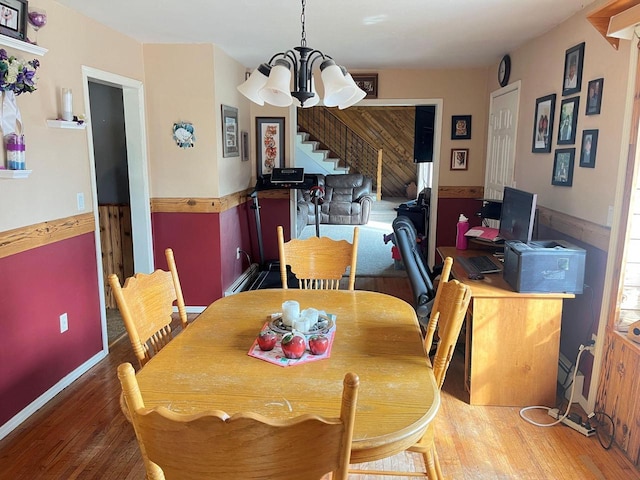 dining area with a chandelier, stairway, and wood finished floors