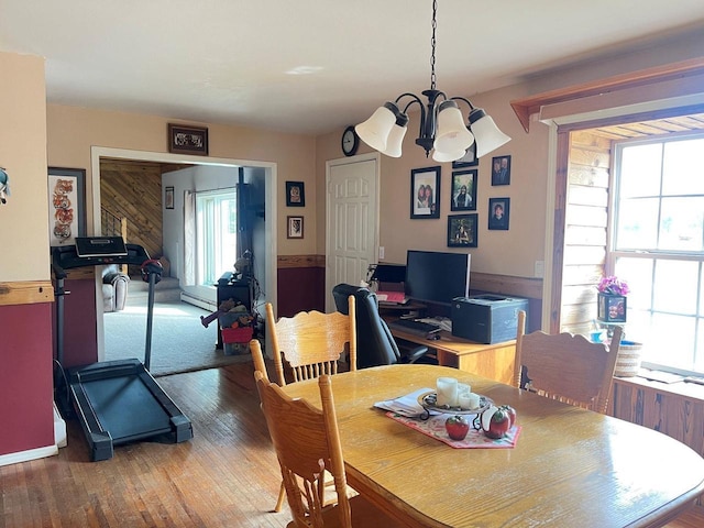 dining area featuring a baseboard radiator, wood-type flooring, and a chandelier