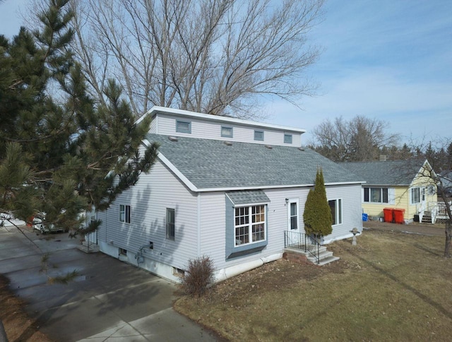 view of front of house featuring a front lawn and a shingled roof