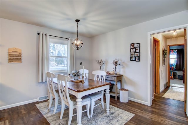 dining area with dark wood-type flooring, baseboards, visible vents, and a chandelier