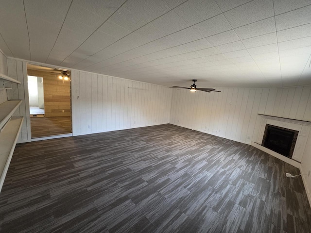 unfurnished living room featuring dark wood-type flooring, a ceiling fan, and a fireplace