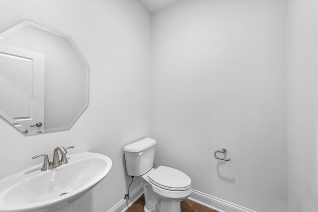 1251 Denmark Cir, Oregon, WI 53575 - half bathroom with toilet, wood finished floors, baseboards, and a sink