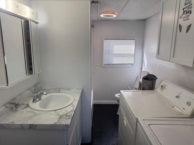 bathroom with baseboards, toilet, vanity, and washer and clothes dryer