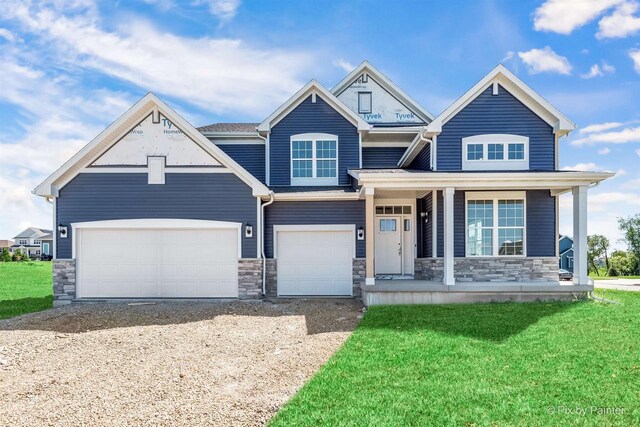 view of front facade with driveway, a porch, a front lawn, a garage, and stone siding