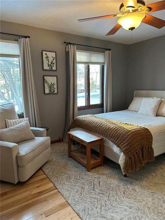 bedroom with a textured ceiling, light wood finished floors, and ceiling fan