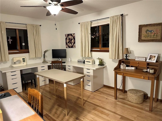 office space featuring baseboards, a ceiling fan, and light wood finished floors