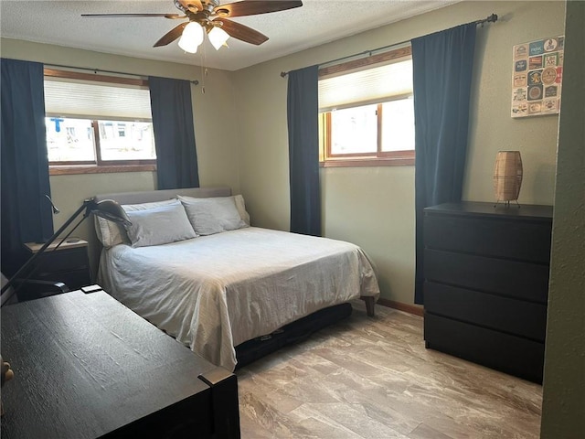 bedroom with baseboards, multiple windows, a textured ceiling, and ceiling fan