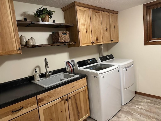 washroom featuring a sink, cabinet space, separate washer and dryer, and a textured ceiling