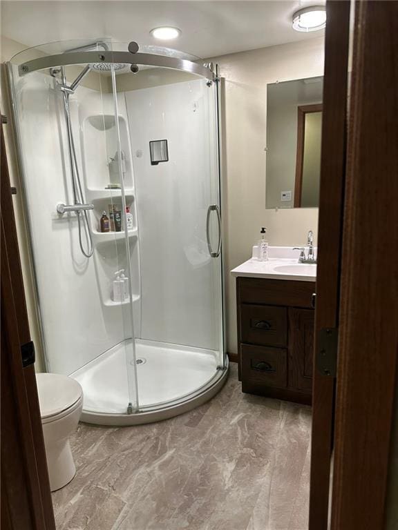 bathroom featuring vanity, a shower stall, and toilet