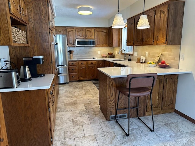 kitchen with visible vents, a peninsula, a sink, stone finish floor, and appliances with stainless steel finishes