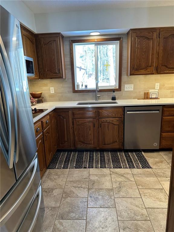 kitchen featuring tasteful backsplash, appliances with stainless steel finishes, light countertops, and a sink