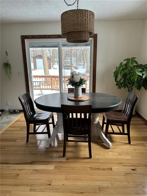 dining room with light wood-style flooring, baseboards, and a textured ceiling