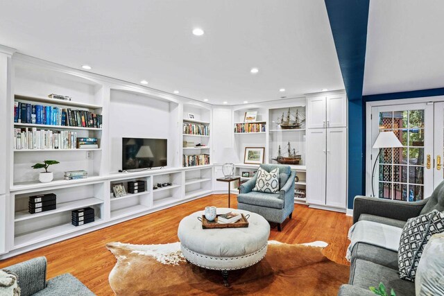 living area featuring built in shelves, recessed lighting, and wood finished floors