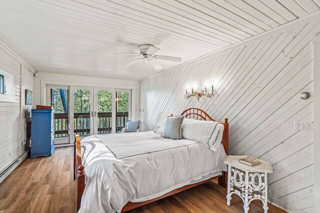 bedroom featuring a baseboard heating unit, french doors, access to exterior, and wood finished floors