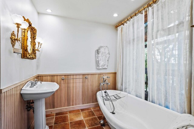 full bathroom featuring a freestanding tub, tile patterned flooring, wooden walls, a wainscoted wall, and a sink