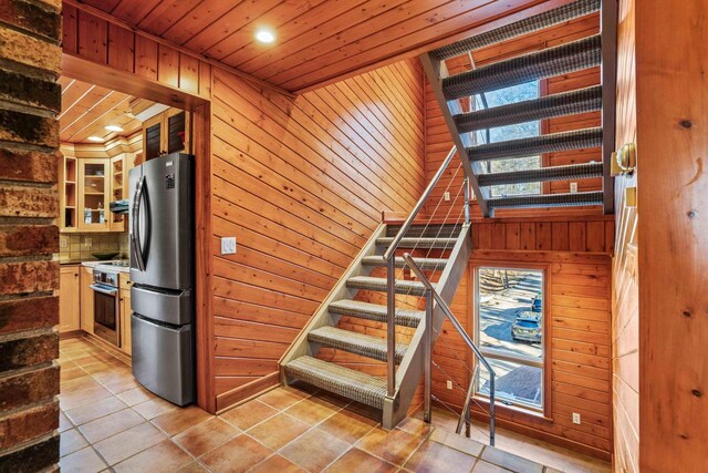 stairs with wooden walls, wooden ceiling, and tile patterned flooring