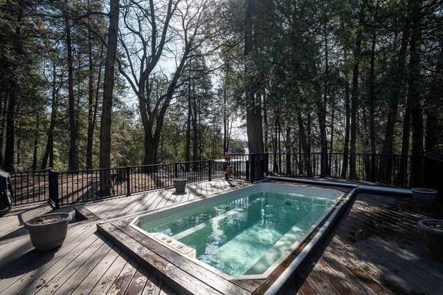 view of pool with an outdoor fire pit, a wooden deck, and hot tub deck surround