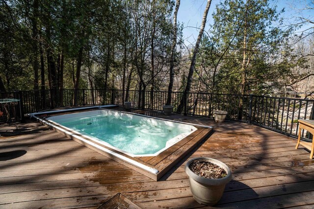 view of swimming pool with a wooden deck and an outdoor hot tub