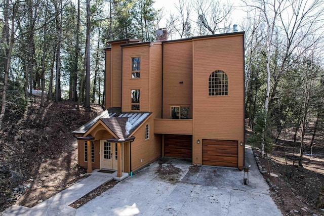 view of front of property featuring a garage, driveway, and a chimney