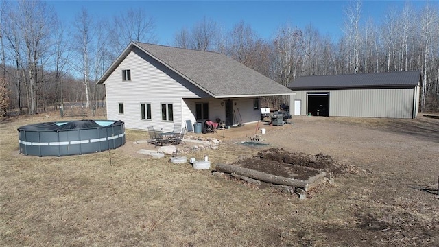 back of property featuring a covered pool, a yard, and an outdoor structure