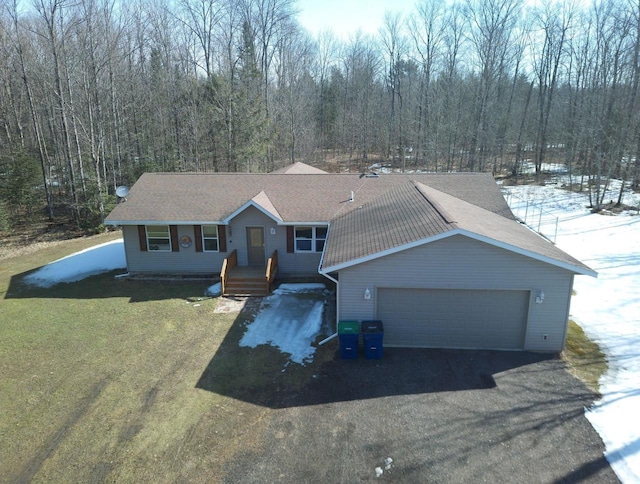 single story home featuring a front lawn, a view of trees, a garage, and a shingled roof