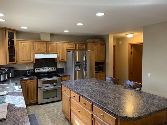 kitchen with under cabinet range hood, recessed lighting, appliances with stainless steel finishes, and dark countertops