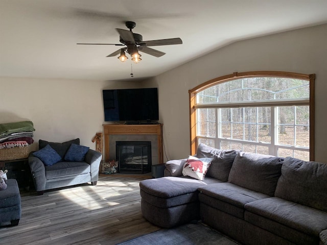 living room with a glass covered fireplace, wood finished floors, and a ceiling fan