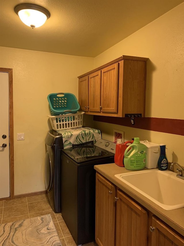 clothes washing area with independent washer and dryer, a sink, a textured ceiling, cabinet space, and light tile patterned floors