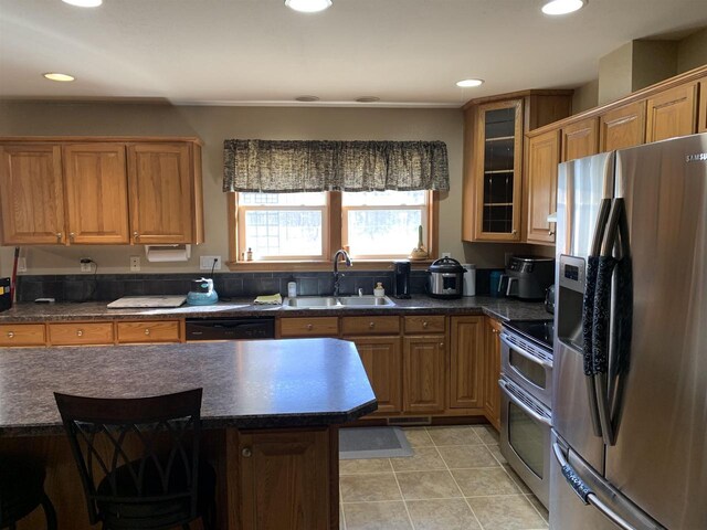 kitchen featuring dark countertops, a breakfast bar, recessed lighting, appliances with stainless steel finishes, and a sink