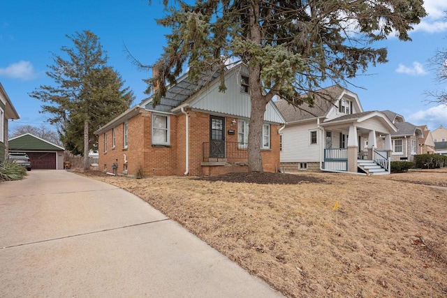 view of front of house with an outbuilding, a garage, covered porch, and brick siding