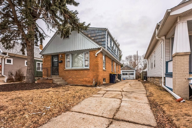 view of front of home with concrete driveway, a detached garage, brick siding, and an outdoor structure