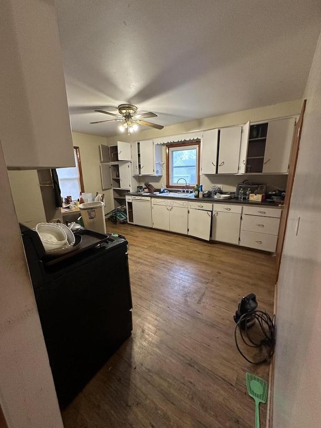 kitchen with a sink, dark countertops, white cabinets, ceiling fan, and dark wood-style flooring