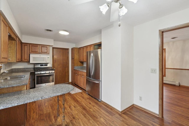 5607 Alben Ave, Mcfarland, WI 53558 - kitchen with a sink, wood finished floors, brown cabinetry, stainless steel appliances, and a baseboard radiator