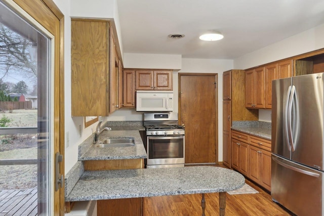 5607 Alben Ave, Mcfarland, WI 53558 - kitchen featuring light stone counters, brown cabinetry, visible vents, a sink, and stainless steel appliances