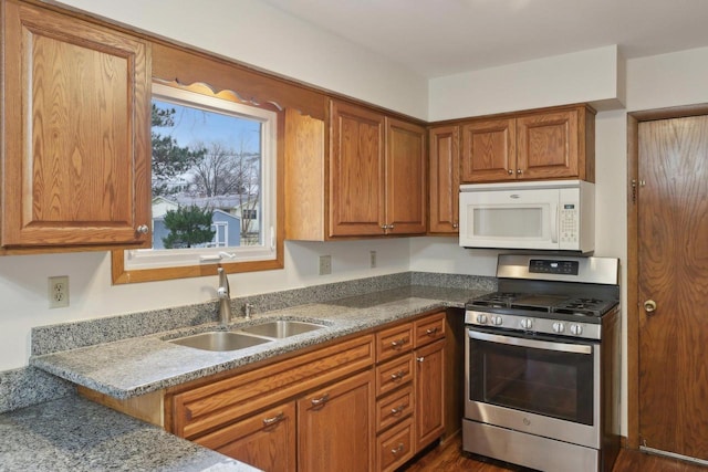 5607 Alben Ave, Mcfarland, WI 53558 - kitchen with stainless steel gas stove, brown cabinets, a sink, light stone counters, and white microwave