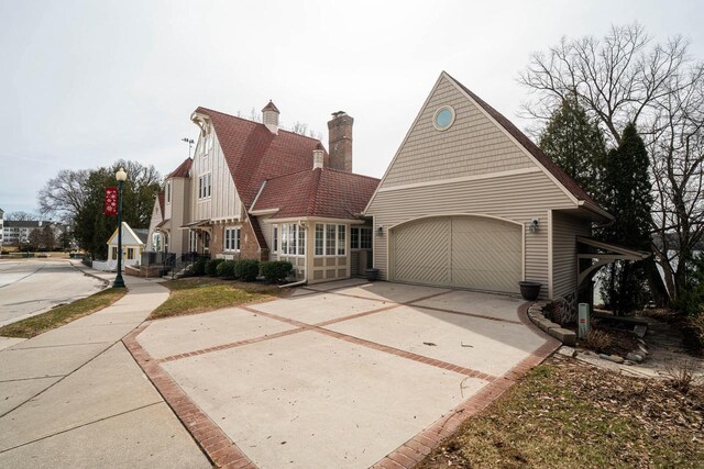 281 S Lake St, Elkhart Lake, WI 53020 - view of front facade featuring concrete driveway, a garage, and a chimney