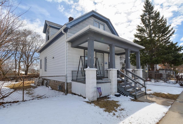 view of front of home featuring a porch, a chimney, and fence