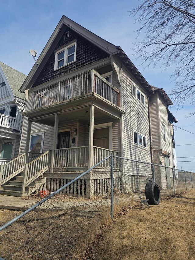 view of front of house featuring a porch, a balcony, and fence