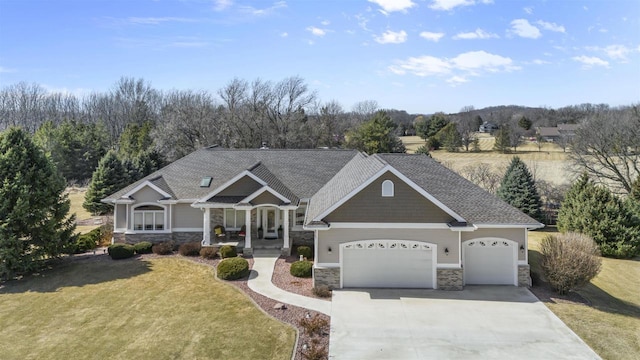 craftsman-style home featuring a garage, stone siding, concrete driveway, and a front yard
