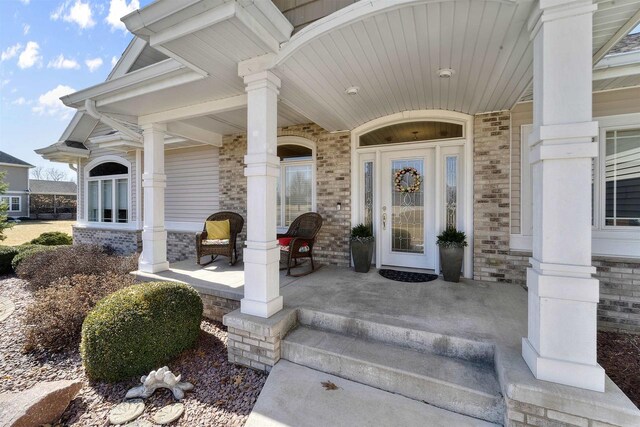 entrance to property with brick siding and a porch