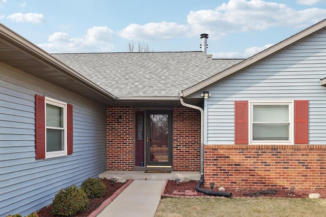 entrance to property with brick siding and a shingled roof