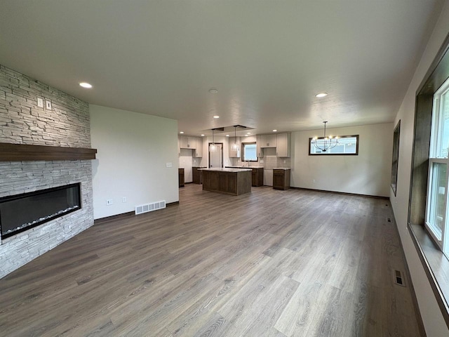 710 Tambour Ct Unit 3, De Pere, WI 54115 - unfurnished living room featuring a chandelier, a fireplace, wood finished floors, baseboards, and recessed lighting