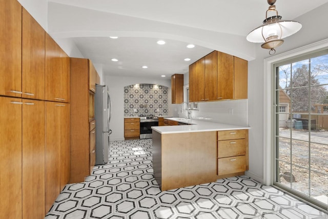 1203 Hewitt St, Neenah, WI 54956 - kitchen with tasteful backsplash, appliances with stainless steel finishes, a peninsula, brown cabinetry, and light countertops