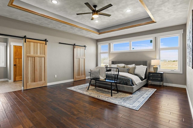 3814 W Fieldwood Dr, Janesville, WI 53545 - bedroom with baseboards, a tray ceiling, a barn door, and dark wood-style flooring