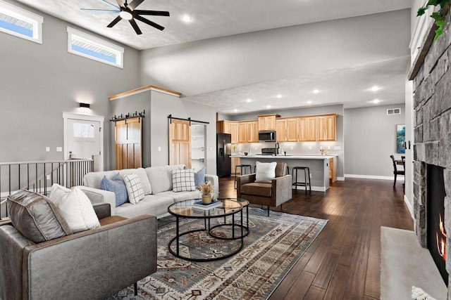3814 W Fieldwood Dr, Janesville, WI 53545 - living area featuring a ceiling fan, dark wood finished floors, a barn door, a stone fireplace, and baseboards