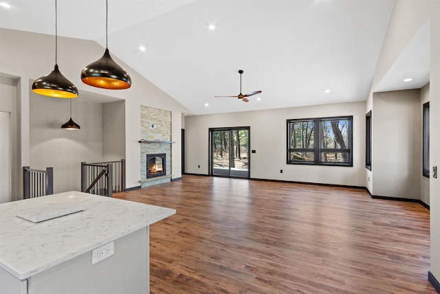 1644 Kingswood Trl, Nekoosa, WI 54457 - unfurnished living room with high vaulted ceiling, ceiling fan, wood finished floors, a stone fireplace, and baseboards