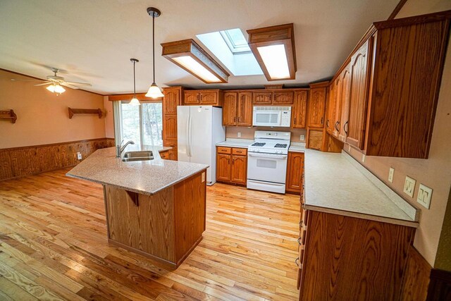 N7957 15th Ave, New Lisbon, WI 53950 - kitchen featuring a wainscoted wall, light countertops, brown cabinetry, white appliances, and a sink